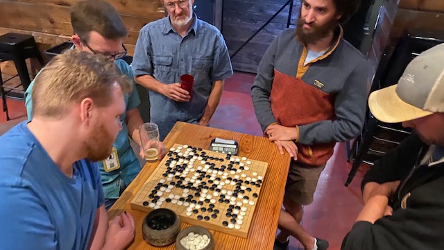 Go Players gathered around a game of Rengo at our Winter venue, Crux
